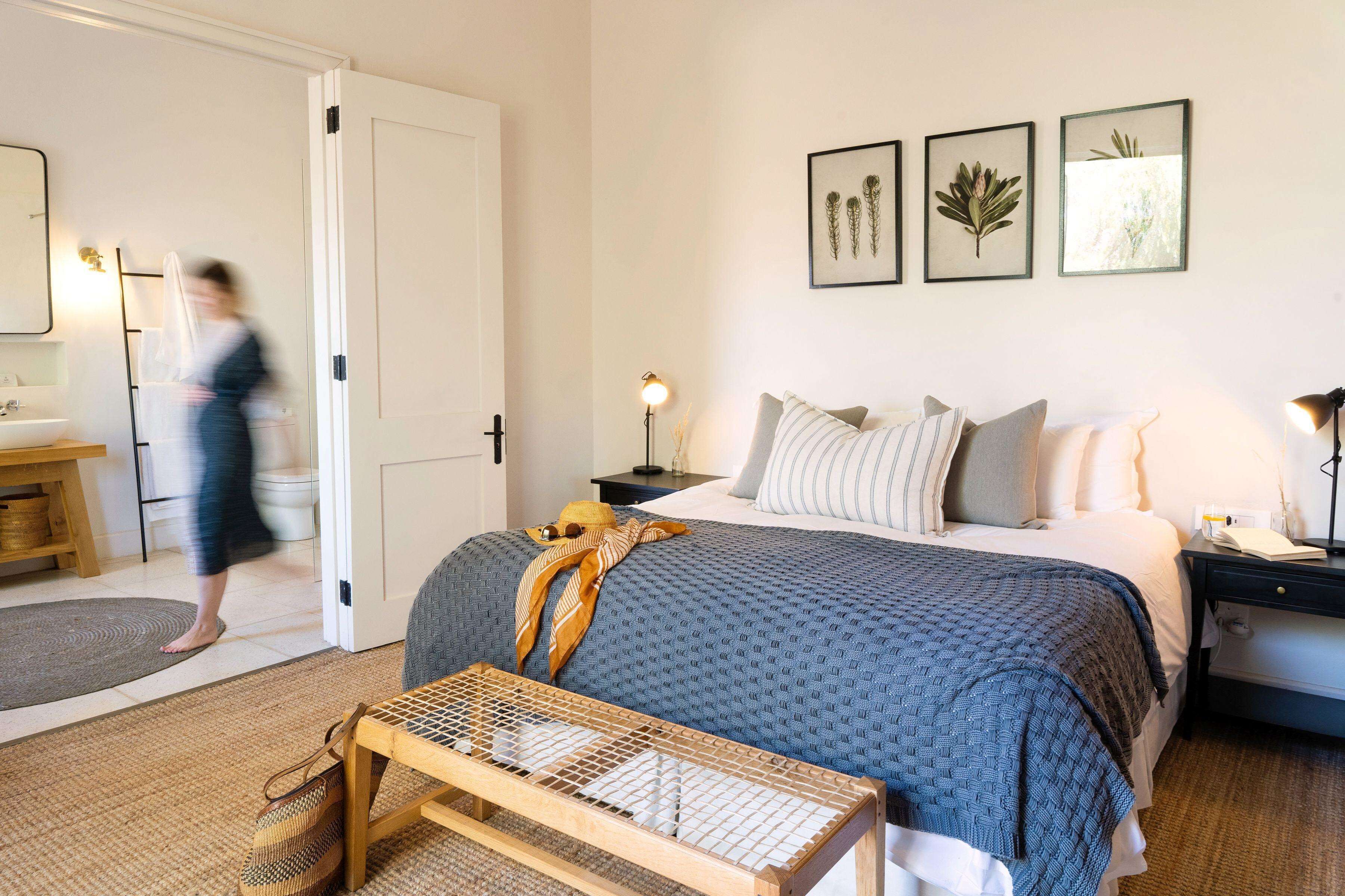 A bedroom with a bed, bedside tables, a nightstand, and a door leading to a bathroom.