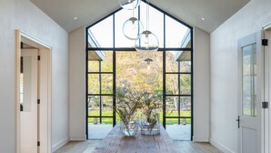 A spacious room with a large wooden table, a view through a large window, and a modern light fixture. - Simbavati Cederberg Ridge (Cederberg)