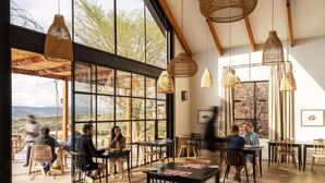 An indoor dining area with large windows, wooden tables, and woven pendant lights. - Simbavati Cederberg Ridge (Cederberg)