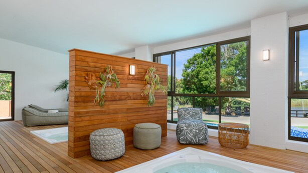 Un área de spa moderna con un separador de madera, una bañera de hidromasaje y asientos.