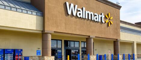 A Walmart store with a large sign, entrance, and Coca-Cola vending machines.