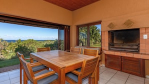 An outdoor dining area with a wooden table and chairs, a brick oven, and a television. - San Lameer Villa Rentals 3704 (Southbroom)