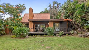 A house with a tiled roof, a balcony, and a garden with various plants. - San Lameer Villa Rentals  2707 (Southbroom)