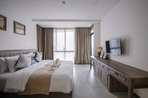 A modern hotel room with a large bed, a flat-screen TV, a wooden dresser, and a large window with curtains. - KAIDA Resort & Residences (Hang Dong)