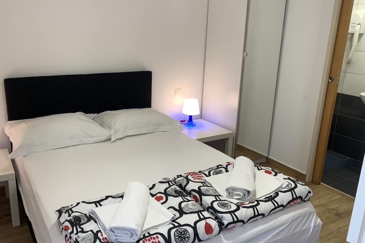 A hotel room with a bed, two bedside tables, two lamps, and a wardrobe.