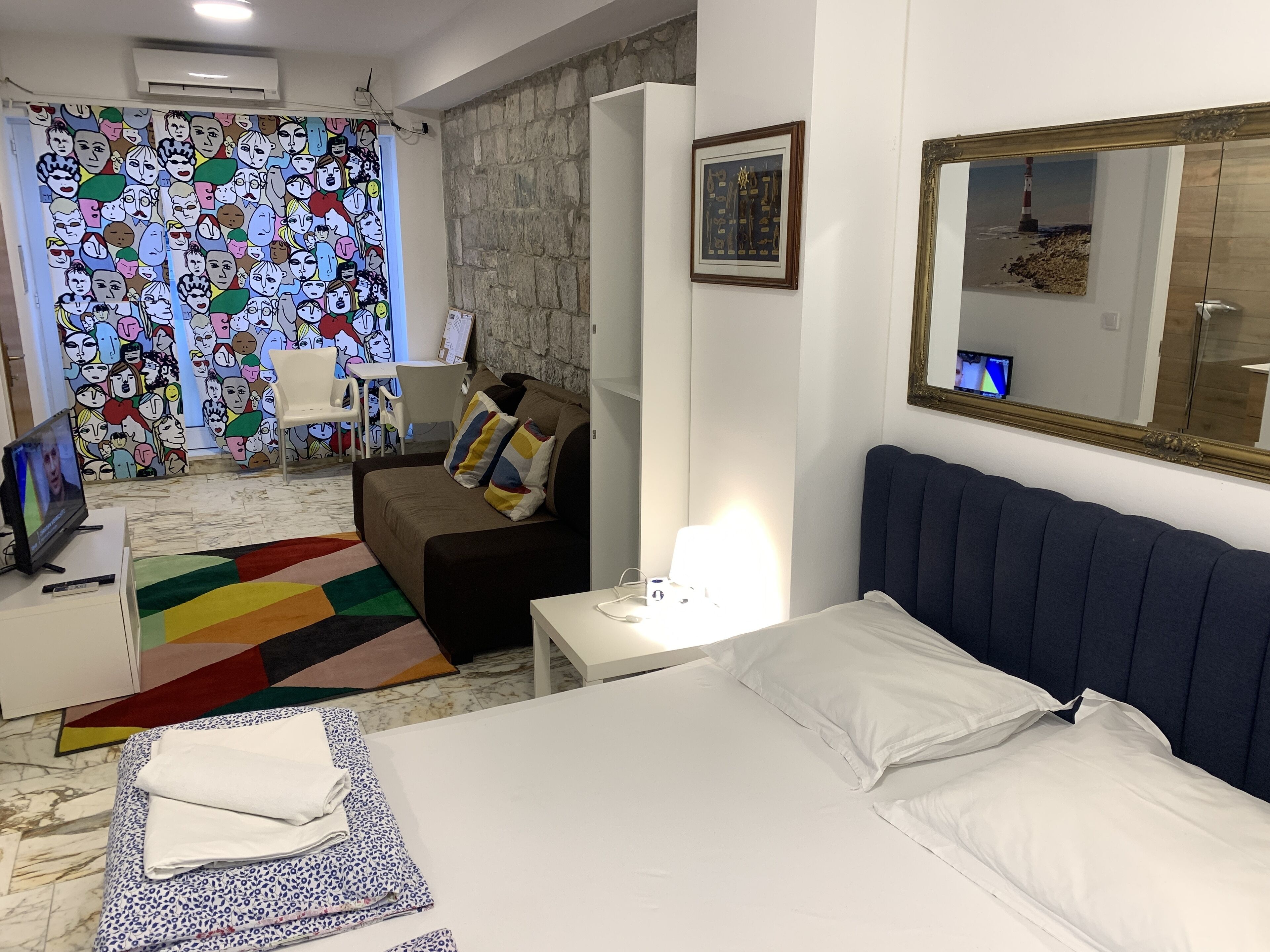 Habitación de hotel con cama, sofá, escritorio, silla y un llamativo mural en la pared.