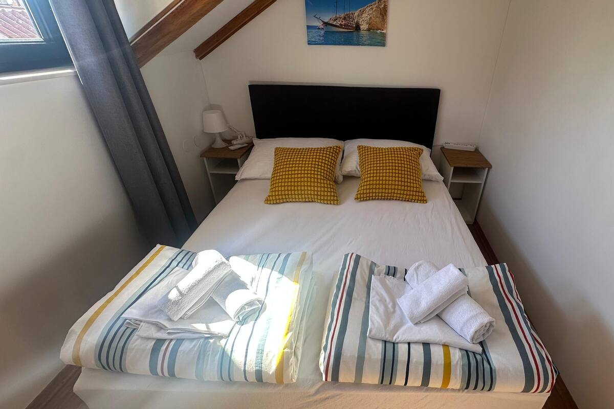 A neatly made bed with striped bedding, two pillows, and a headboard.
