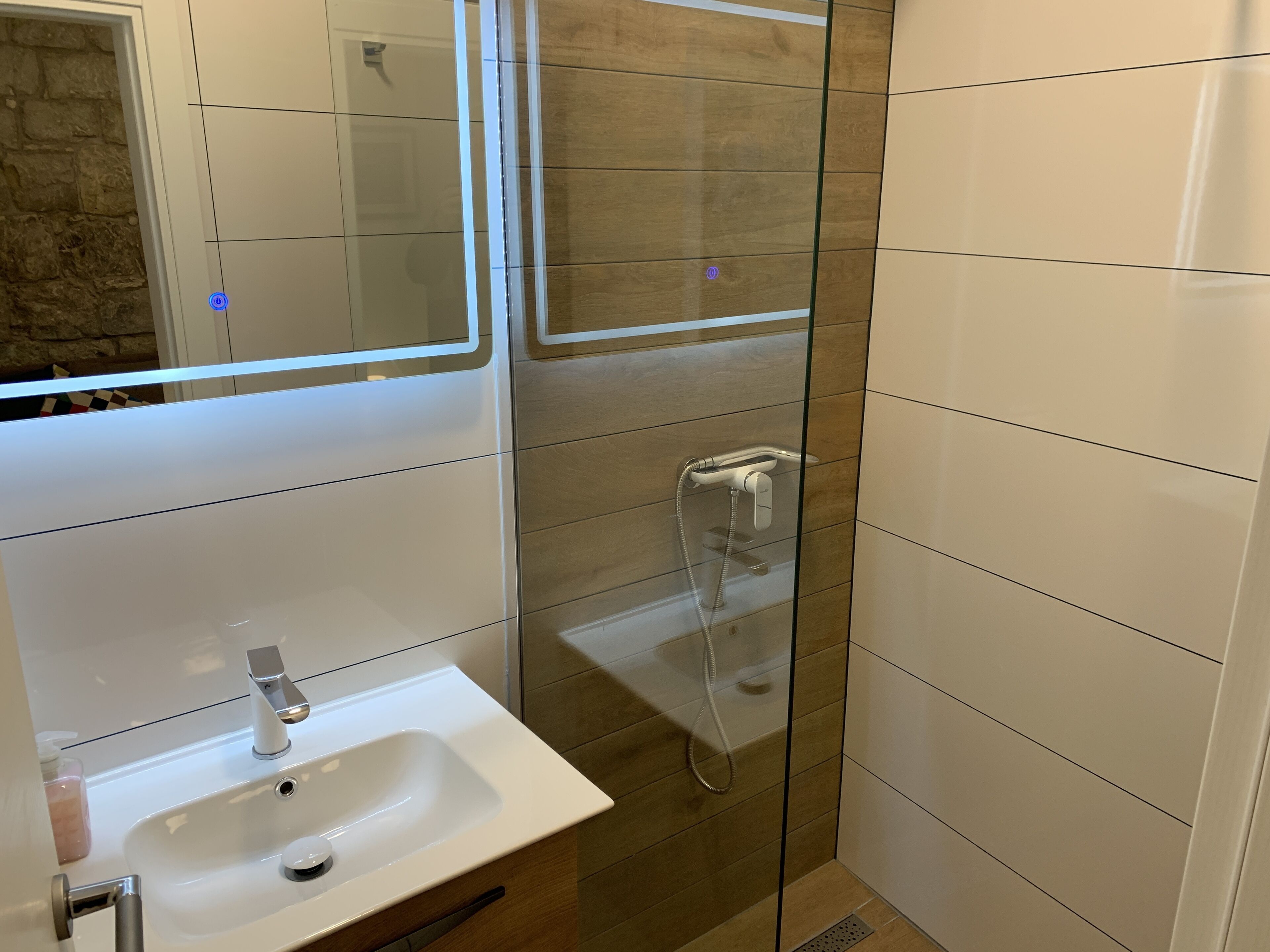 Un baño con ducha de vidrio, lavabo blanco y espejo.