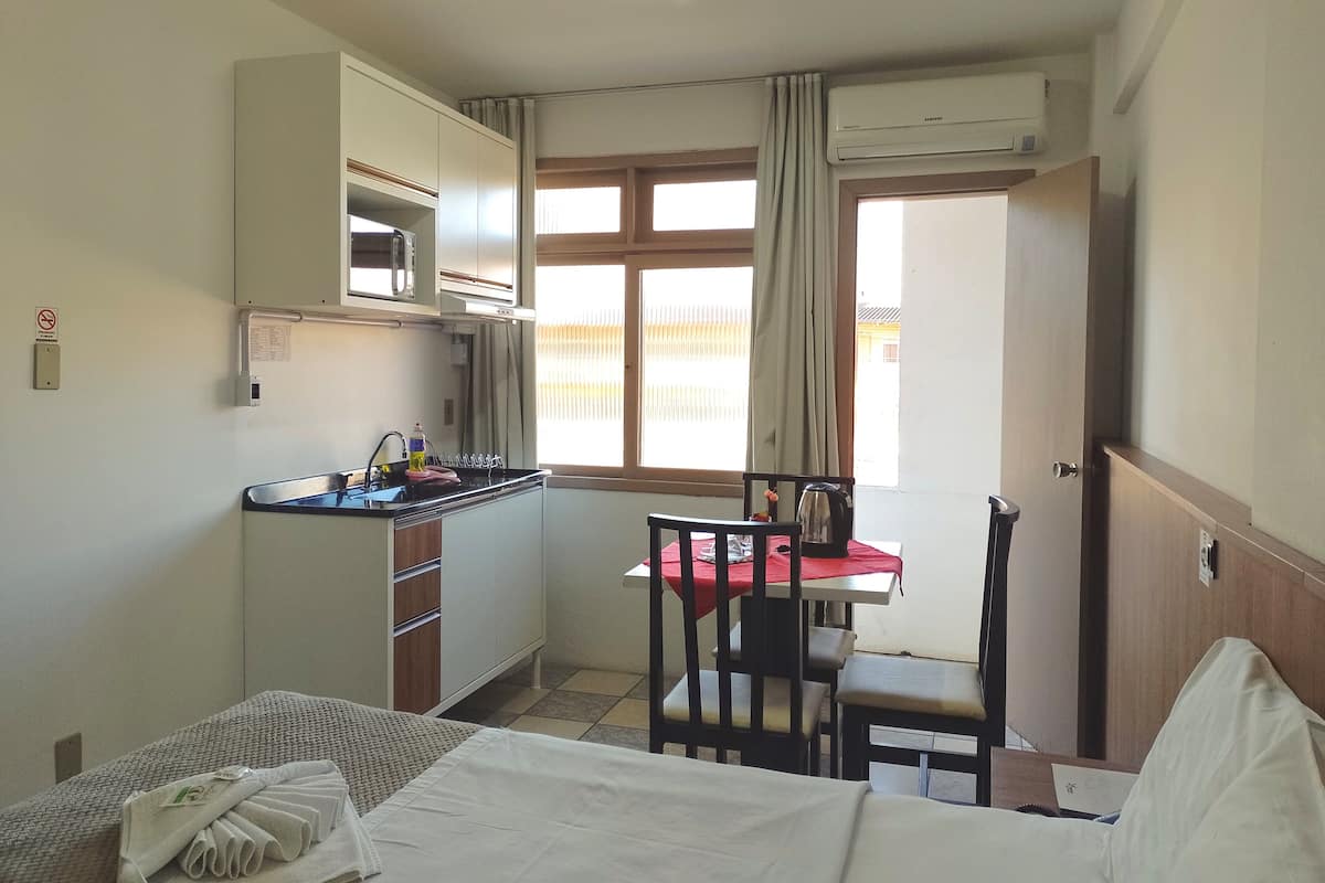 Habitación de hotel compacta con kitchenette, zona de comedor y cama.
