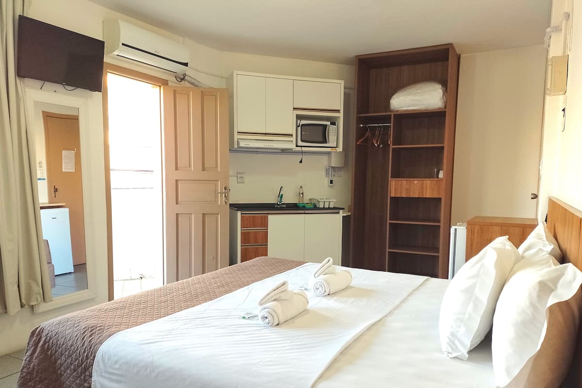 Habitación de hotel con cama, microondas, kitchenette pequeña y armario.