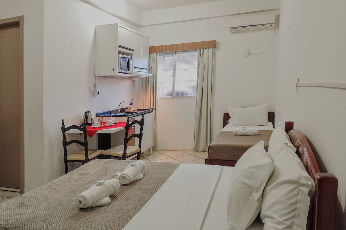 Habitación de hotel con dos camas, un escritorio, un microondas y un ventanal con cortinas.