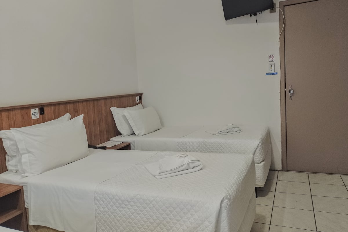 Habitación de hotel con dos camas, un televisor montado en la pared y una puerta con cerradura.