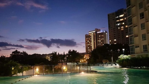 A swimming pool area with a fence, surrounded by buildings with illuminated windows. - 1209 Two Residences Marco Polo Cebu (Cebu City)