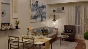 A modern living room with a dining area, featuring a chandelier, a sofa, a coffee table, and a chair. - 1209 Two Residences Marco Polo Cebu (Cebu City)
