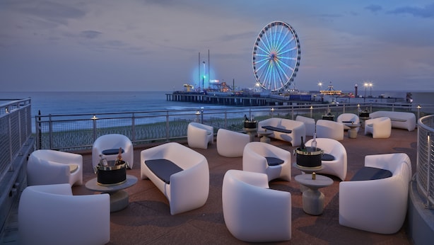 A rooftop bar with white cushioned seating and a large Ferris wheel in the background. - Hard Rock Hotel & Casino Atlantic City (Atlantic City)