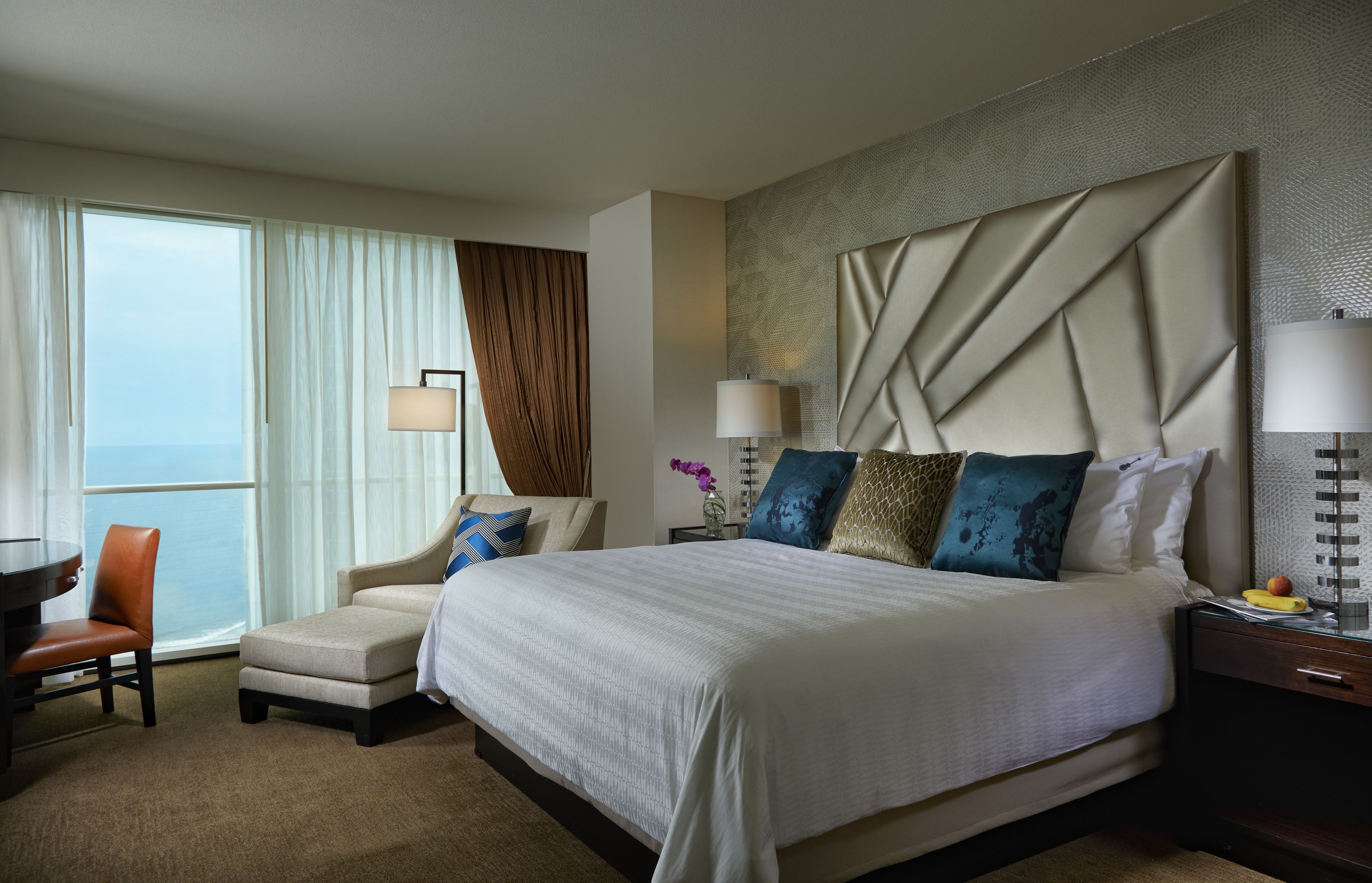 Habitación de hotel con una cama grande, un sofá, un escritorio y vista al océano.