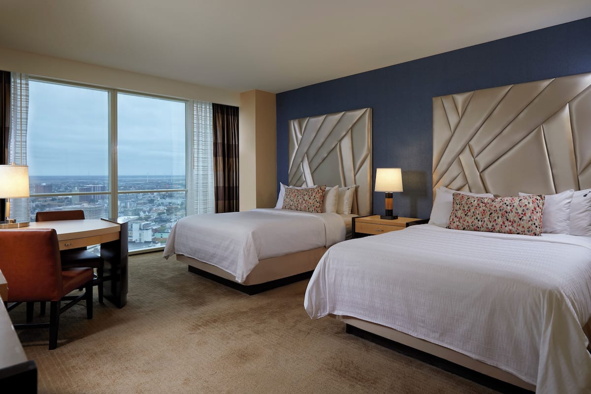 A hotel room with two beds, a desk, and a chair.
