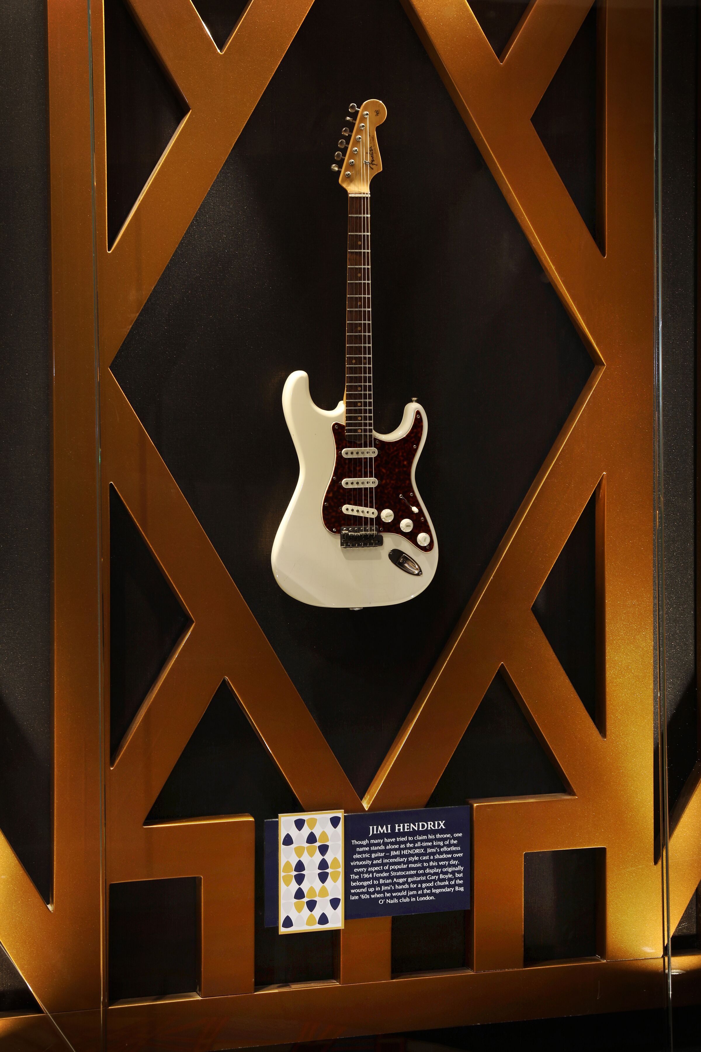 A framed electric guitar with a label and a small card below it.