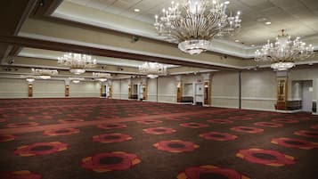 A large, carpeted room with multiple chandeliers and doors.