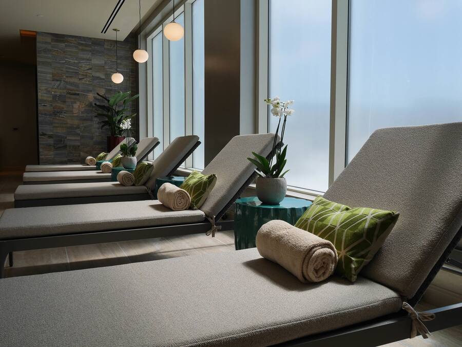 A spa room with reclining chairs, towels, and potted plants.