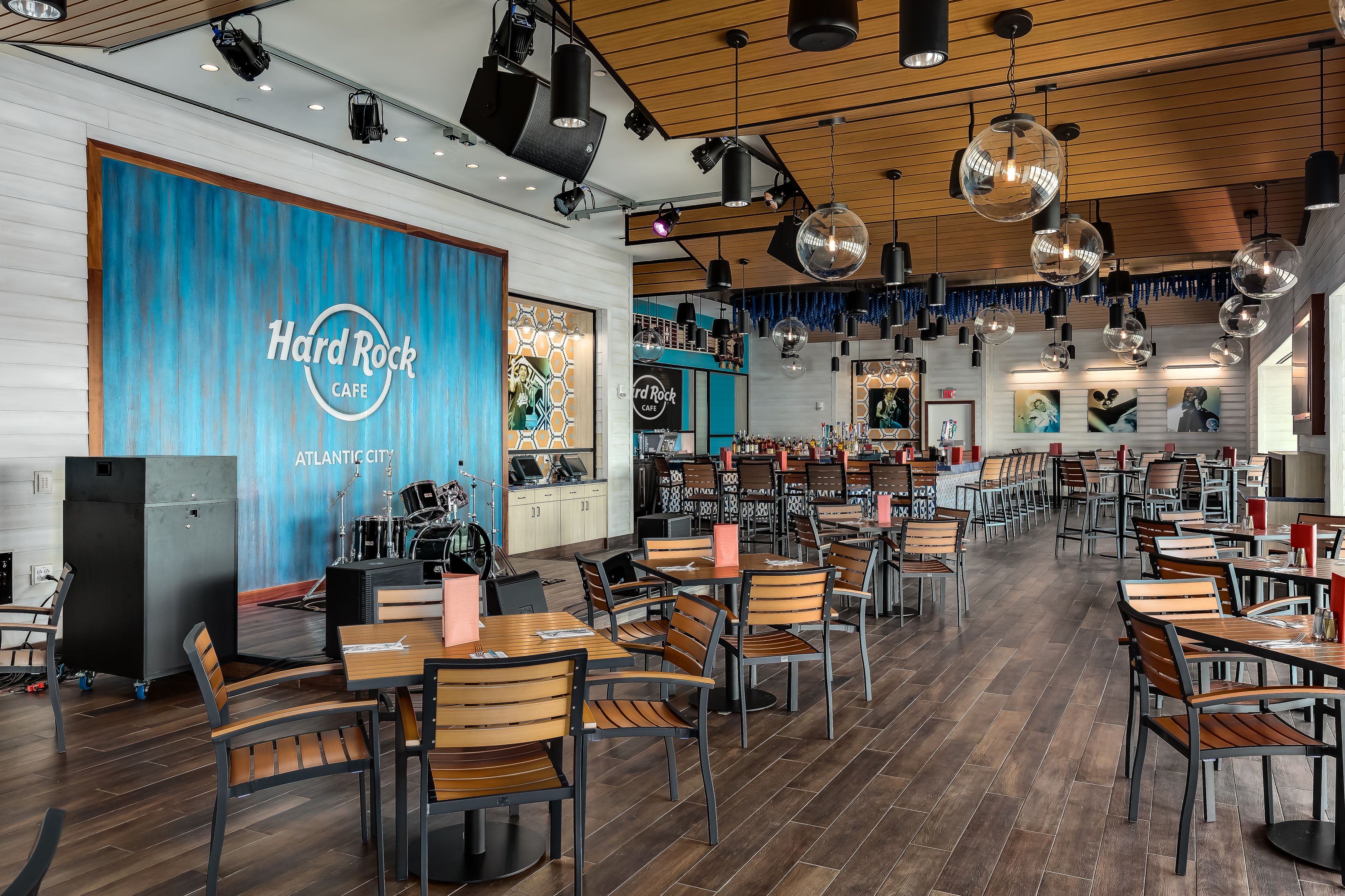 Een Hard Rock Cafe interieur met meerdere tafels en stoelen, een podium en een blauwe muur met het logo van de café.