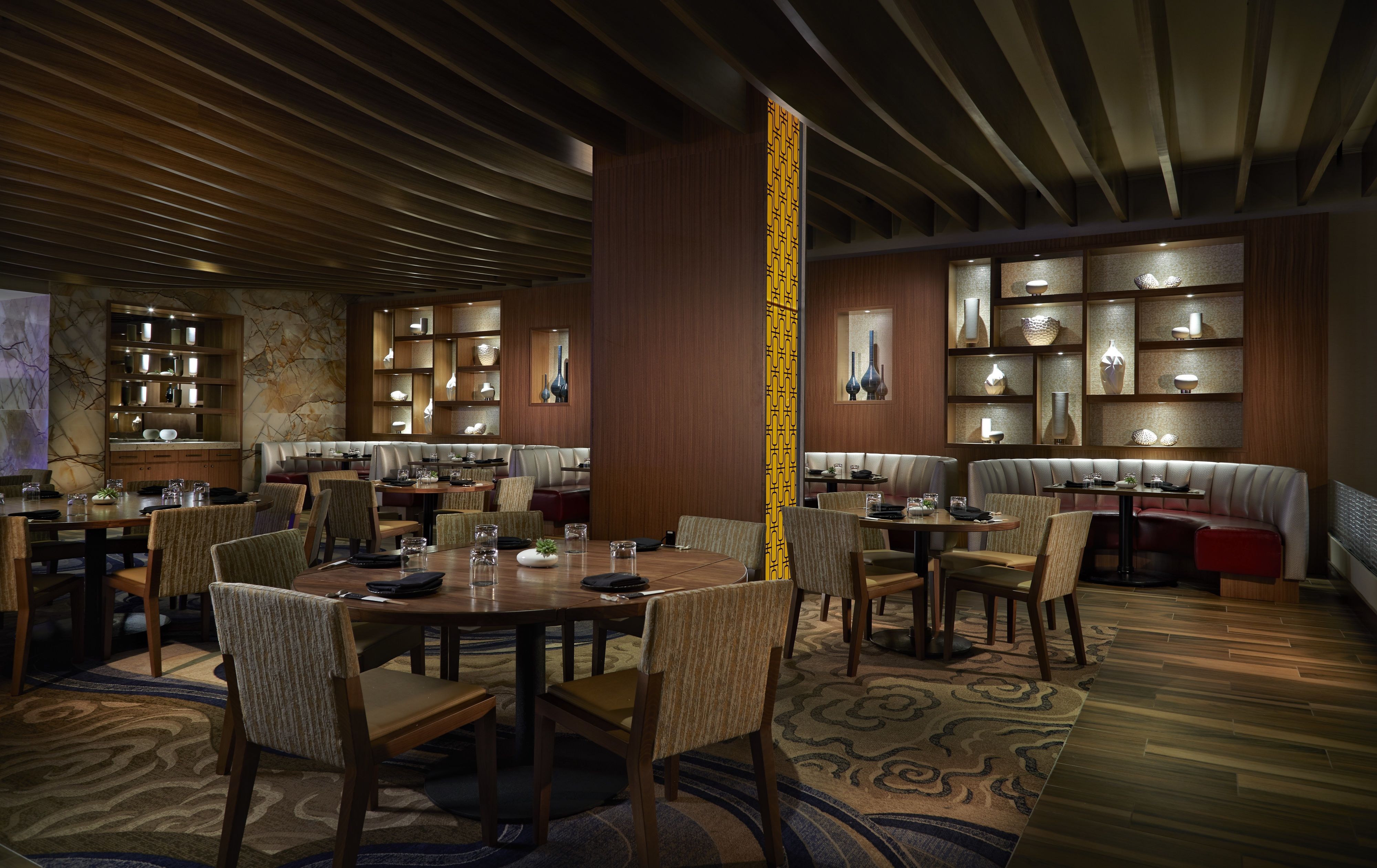 A restaurant with round tables, cushioned booths, and a patterned wall.