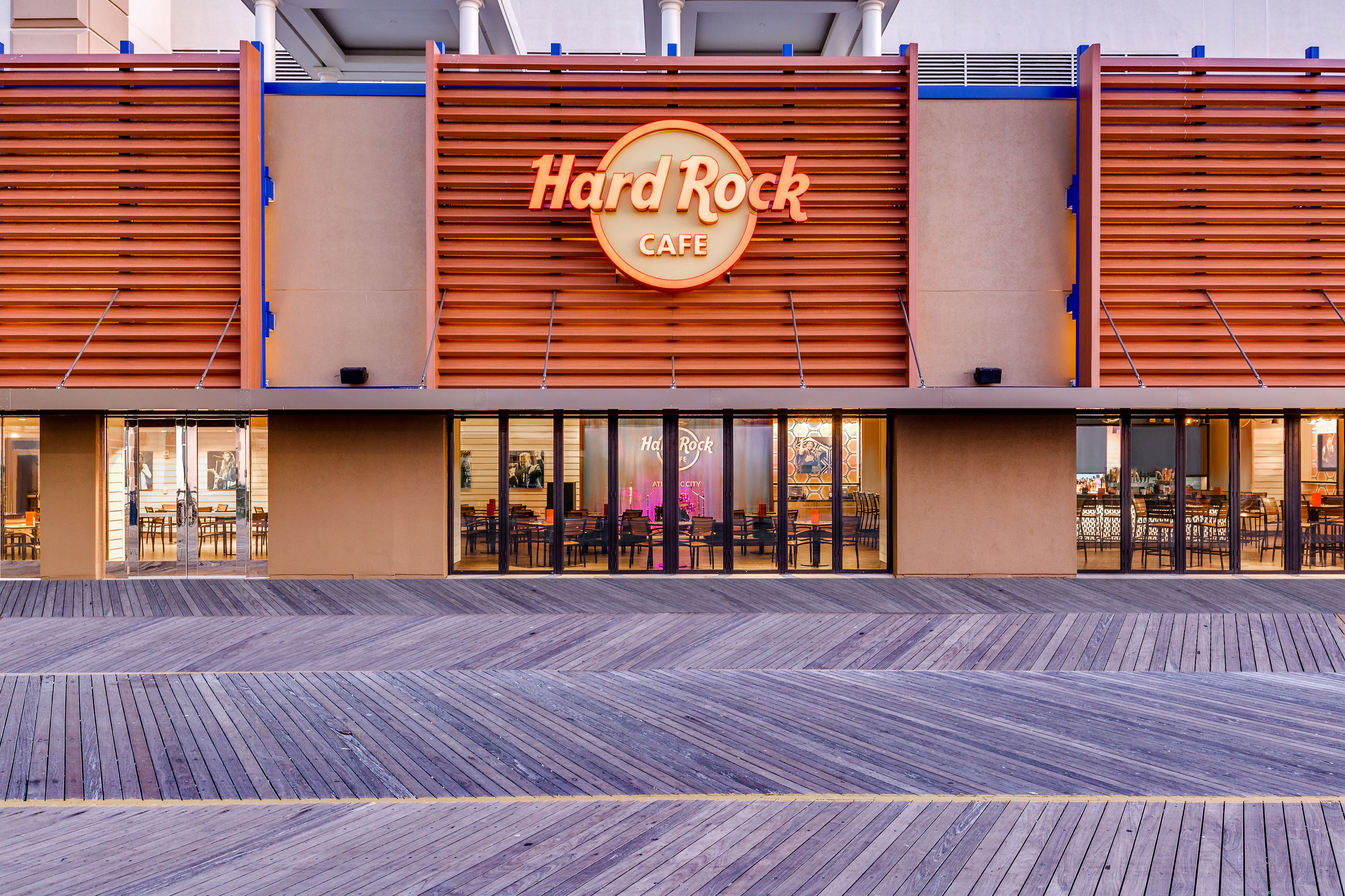 Ein Hard Rock Cafe mit modernem Design, das ein markantes Schild und einen großzügigen Außenbereich zum Sitzen bietet.