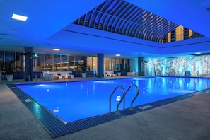 A large indoor swimming pool with clear blue water, surrounded by lounge areas with seating and potted plants. - Hard Rock Hotel & Casino Atlantic City (Atlantic City)