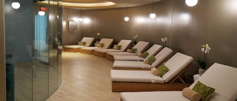 Un moderno spa con múltiples sillones de descanso, un muro de vidrio e iluminación empotrada en el techo.