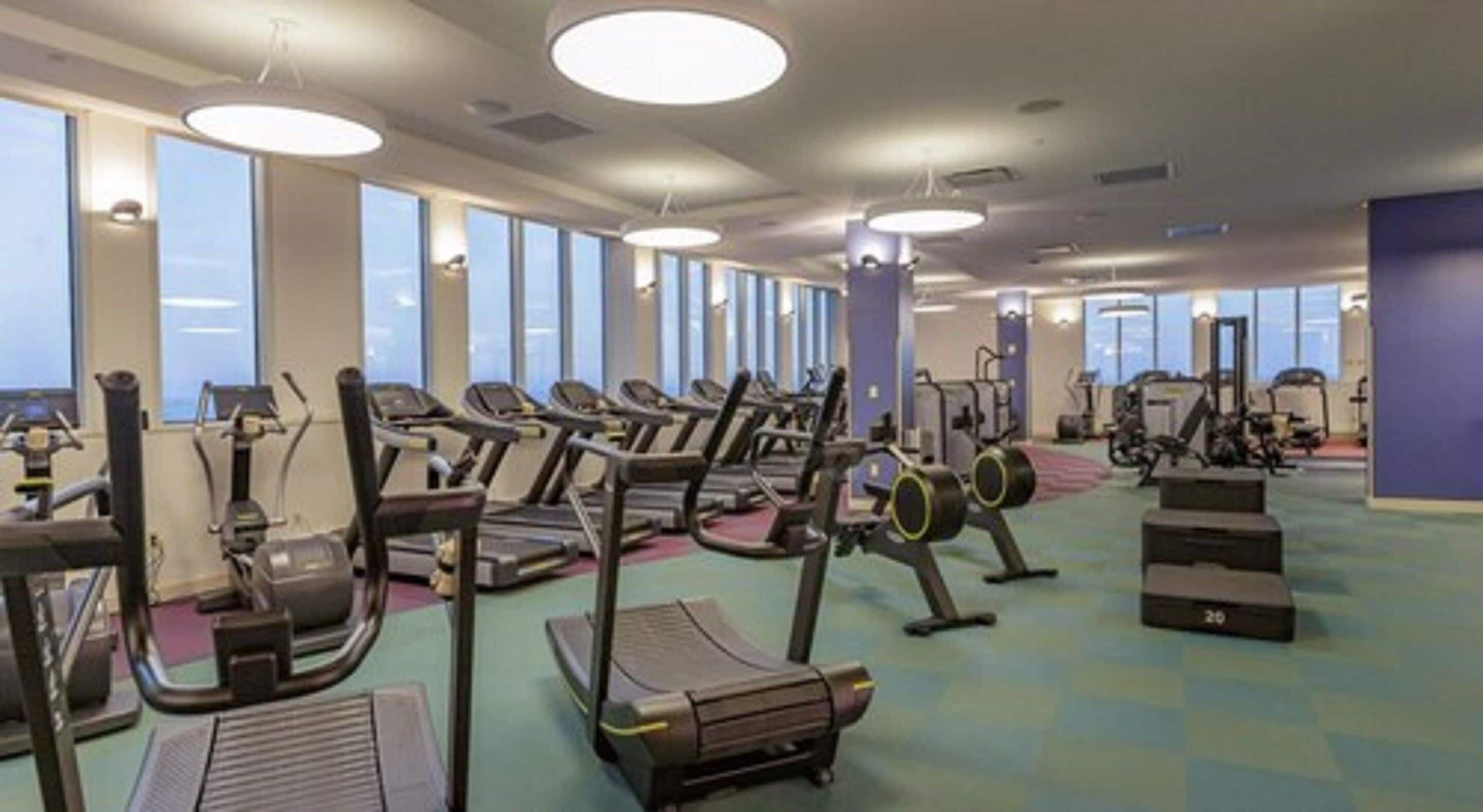 Un gimnasio con cintas de correr, elípticas y equipo de pesas.