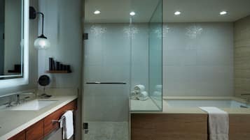 A modern bathroom with a glass shower enclosure, a large mirror, and a vanity with a sink and towel rack.