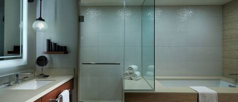 A modern bathroom with a glass shower enclosure, a large mirror, and a vanity with a sink and towel rack.