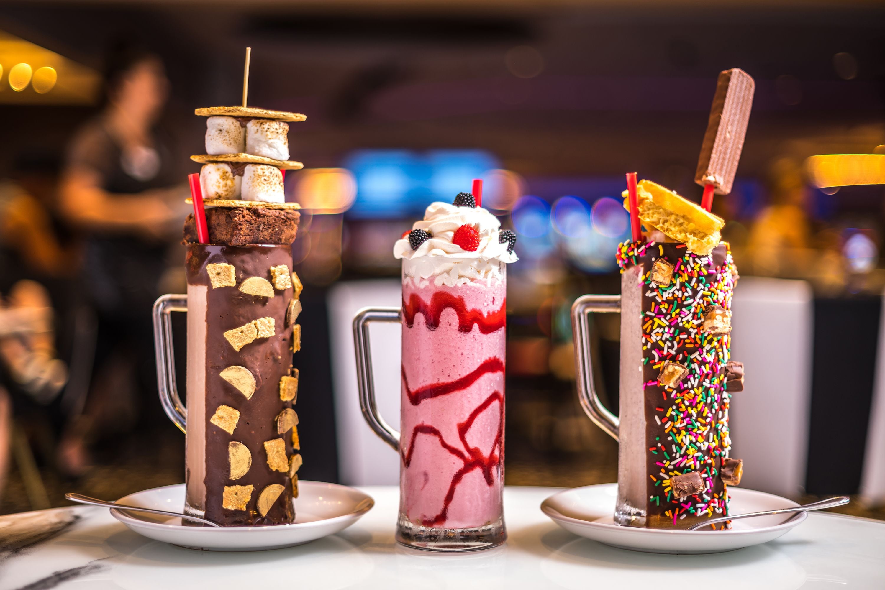 Trois boissons dessert servies dans de grands verres, posées sur une table.