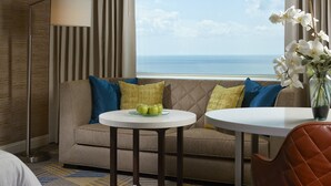 A hotel room with a sofa, a small round table, a chair, a floor lamp, and a view of the ocean. - Hard Rock Hotel & Casino Atlantic City (Atlantic City)
