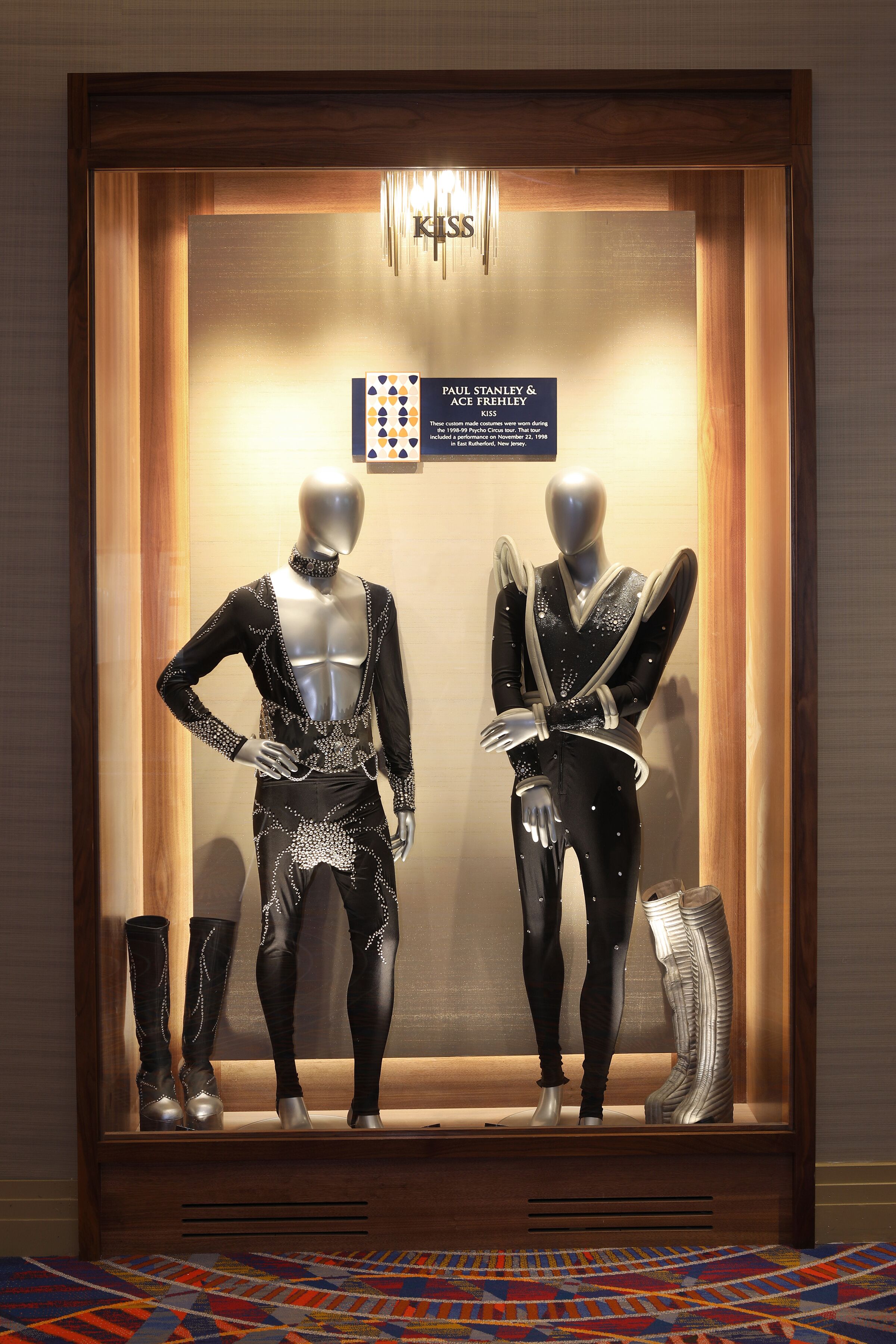 Maniquíes en el escaparate de una tienda exhiben una variedad de ropa y calzado en negro y plateado.