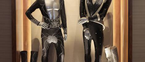 Maniquíes en el escaparate de una tienda exhiben una variedad de ropa y calzado en negro y plateado.
