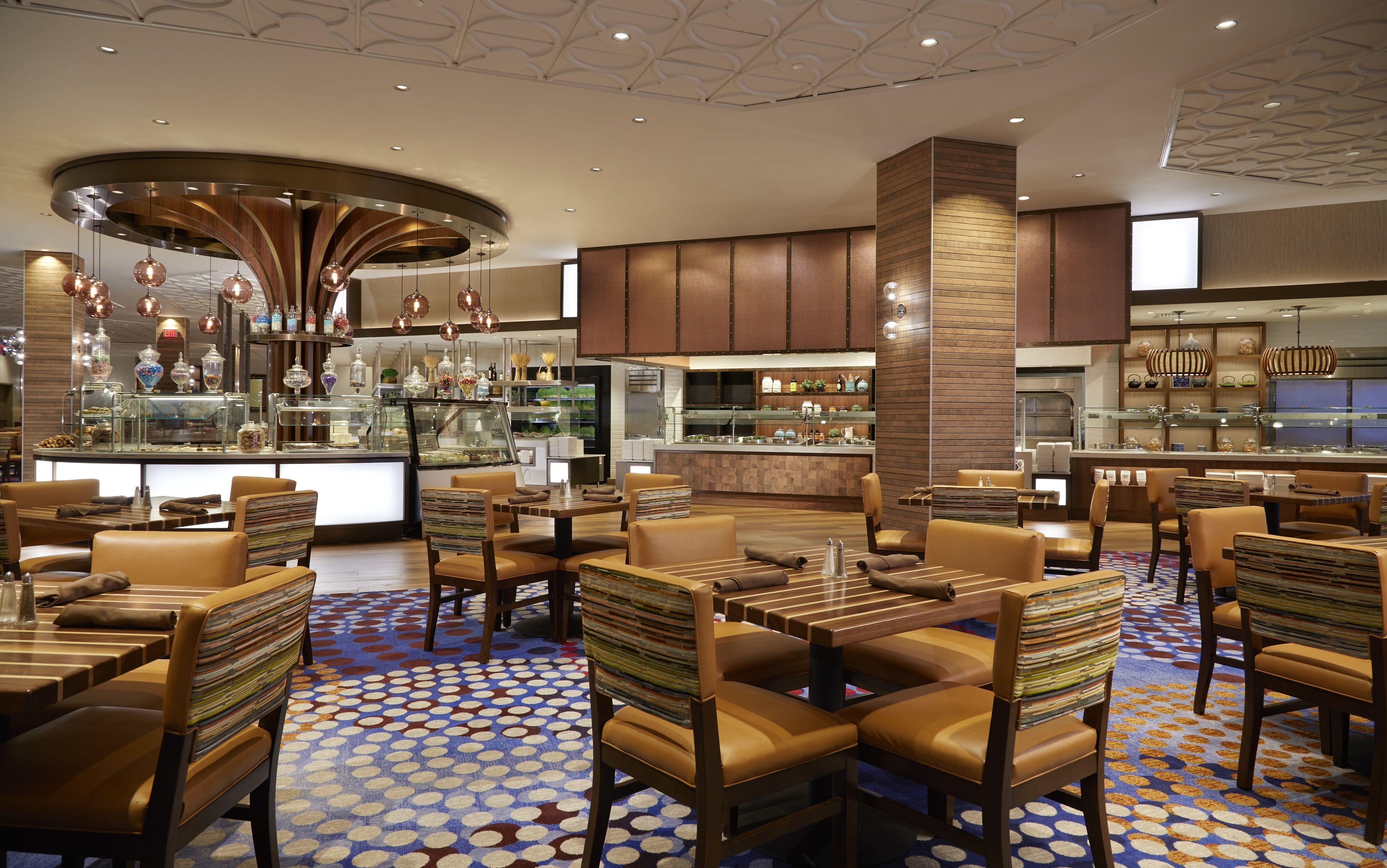 A modern hotel lobby with a central bar area, seating arrangements, and a patterned floor.