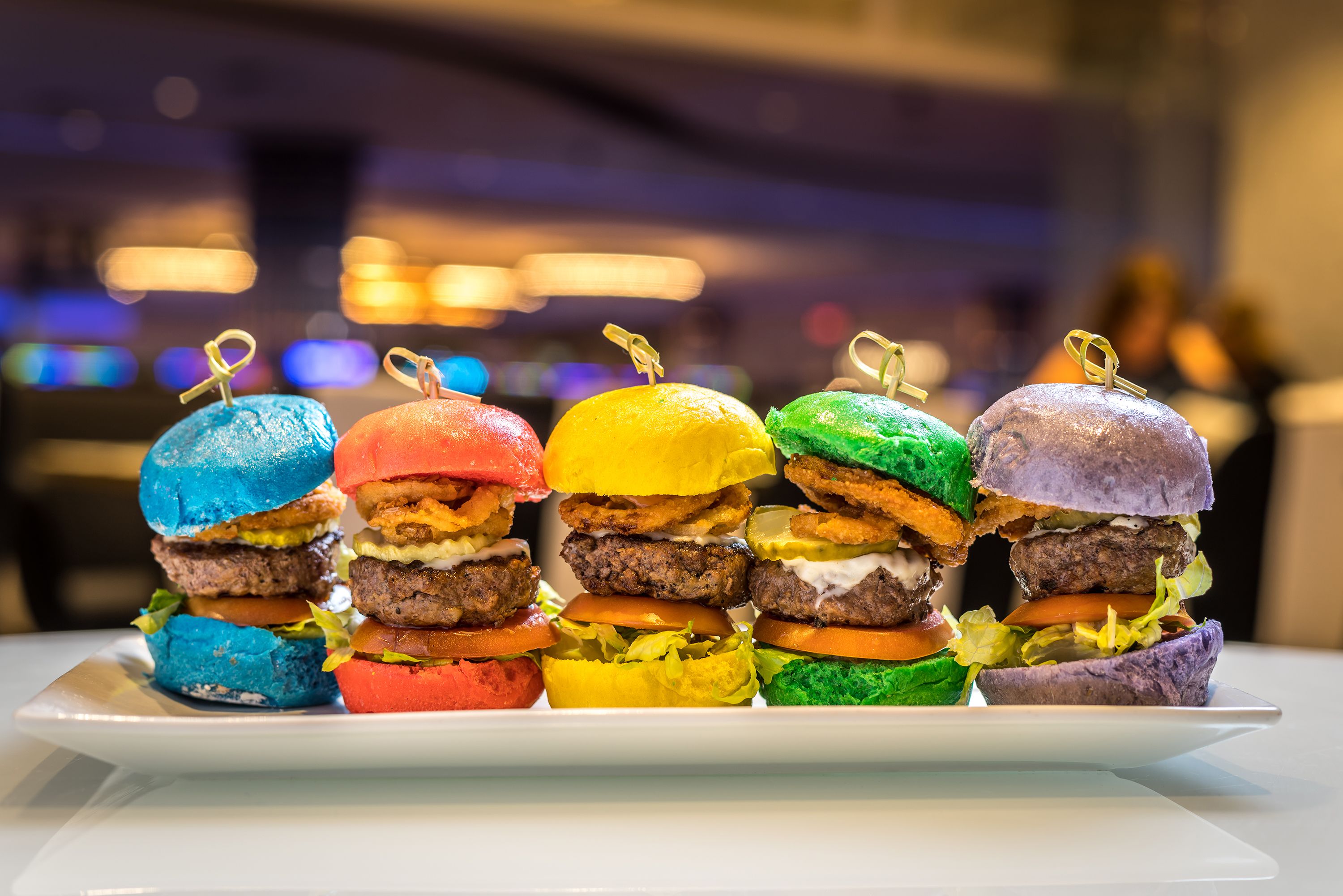 A tray of colorful burgers with a blurred background.