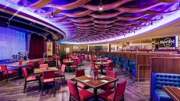 Ein Restaurant mit roten und blauen Sitzgelegenheiten, einer Bühne und einem Hard Rock Cafe Schild.