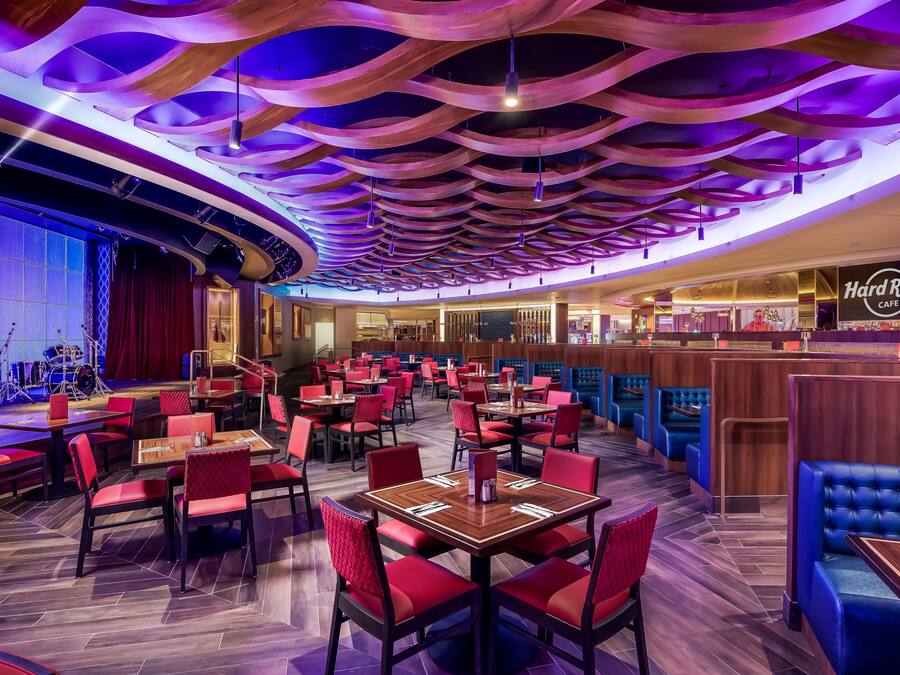 Ein Restaurant mit roten und blauen Sitzgelegenheiten, einer Bühne und einem Hard Rock Cafe Schild.