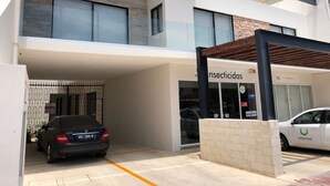 A modern building with a car parked in the driveway and another car in the parking lot. - Downtown Suites Cancun (Cancun)
