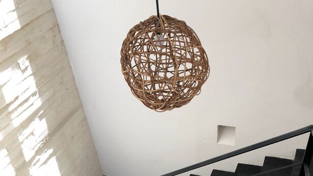 A staircase with a black railing, a woven light fixture, and a wooden bench. - Downtown Suites Cancun (Cancun)