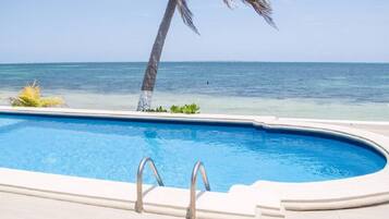 Una piscina al aire libre, sombrillas, sillones reclinables de piscina