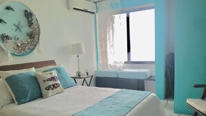 A bedroom with a bed, a nightstand, a lamp, a window with curtains, and a view of the outside. - Flamingo Beach Plus (Cancun)