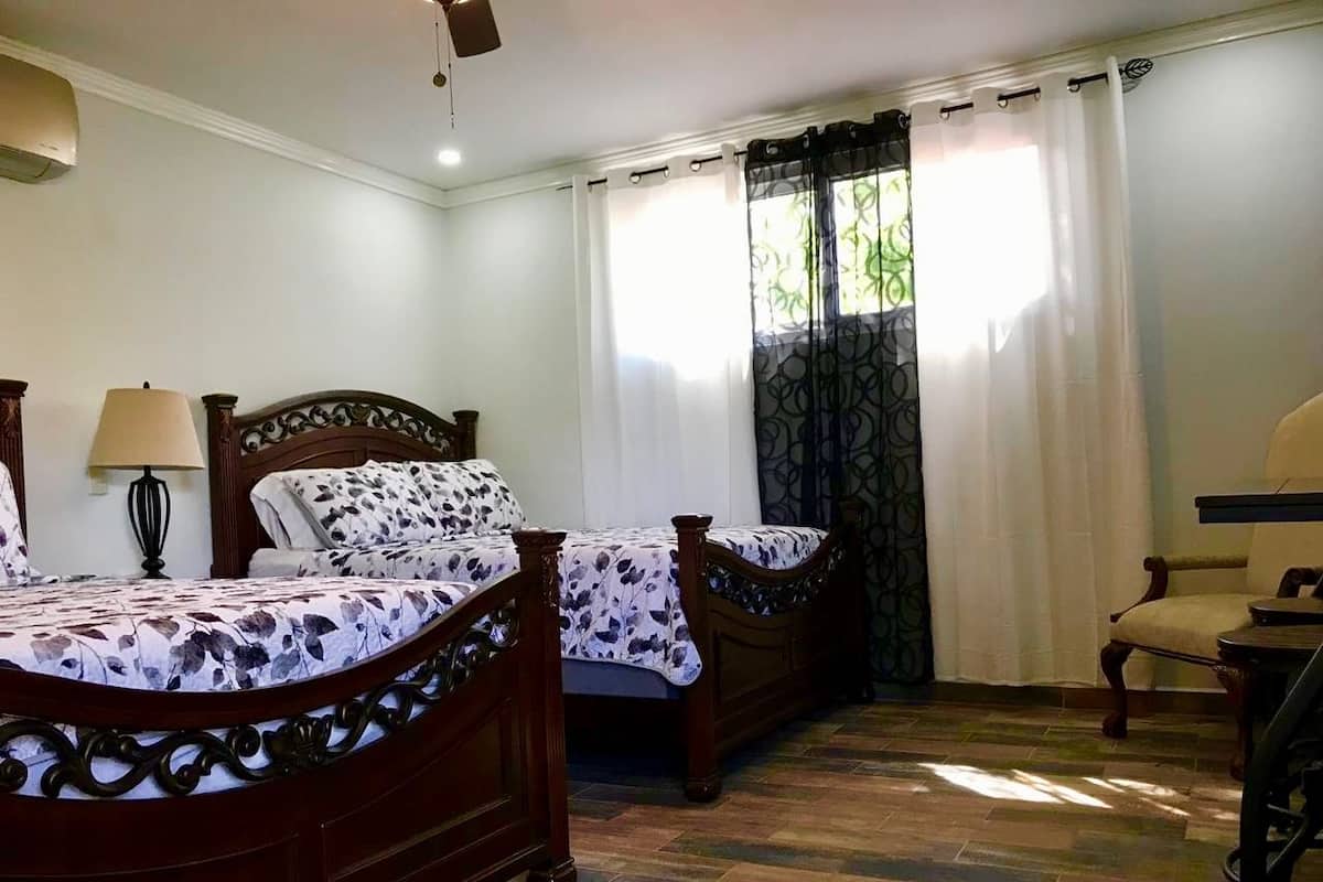 Une chambre à coucher avec deux lits en bois, une chaise et une table.