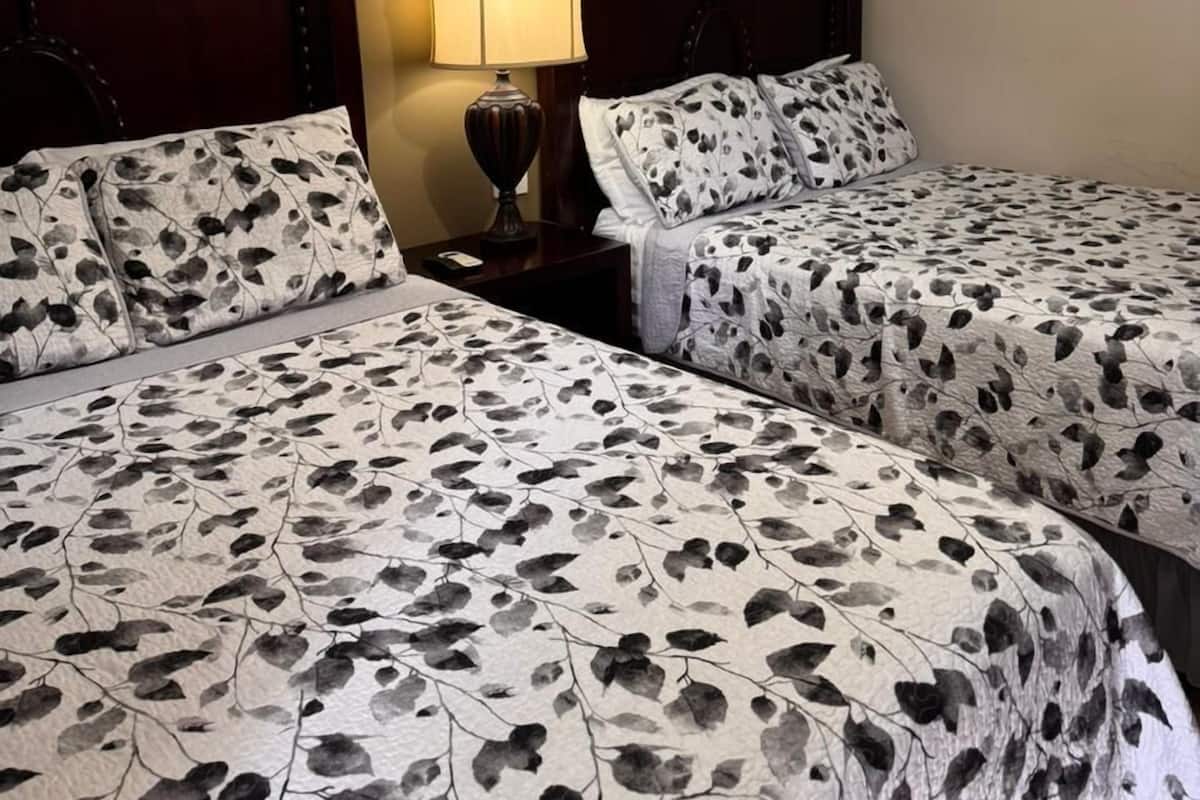 Une chambre d’hôtel avec deux lits, une horloge et une lampe sur une table de chevet.