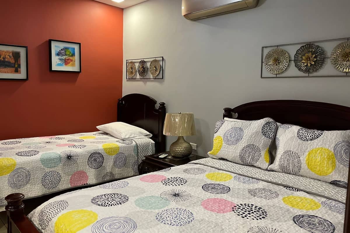Une chambre avec deux lits, un ventilateur de plafond, un climatiseur et des œuvres d’art murales.