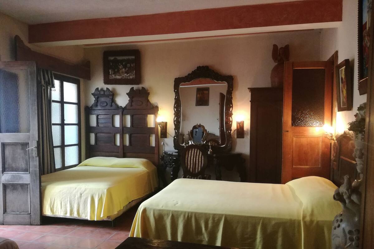 A room with two beds, a wooden wardrobe, a mirror, and a table with a magazine.