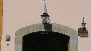 A building entrance with a stone archway, a street lamp, and a sign reading "San Sebastian". - Posada San Sebastian (Antigua Guatemala)