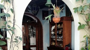 An interior courtyard with a wooden chair, a blue tricycle, and a potted plant. - Posada San Sebastian (Antigua Guatemala)
